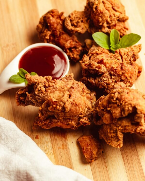 Delicious crispy fried chicken served with a tangy dipping sauce on a wooden board.