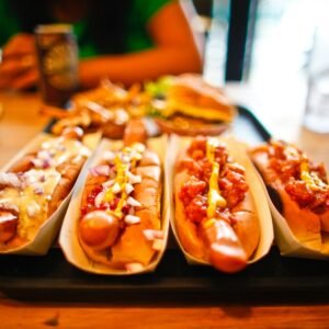 Close-up of various hotdogs with toppings on a wooden table, ideal for fast food themes.