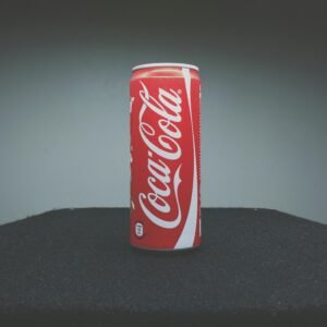 A classic Coca-Cola can showcased on a dark surface with minimal lighting.